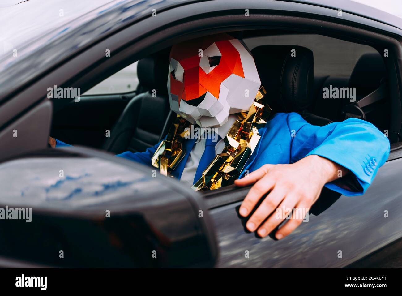 Lustige Figur trägt Tiermaske und blauen Business-Anzug im Auto Stockfoto