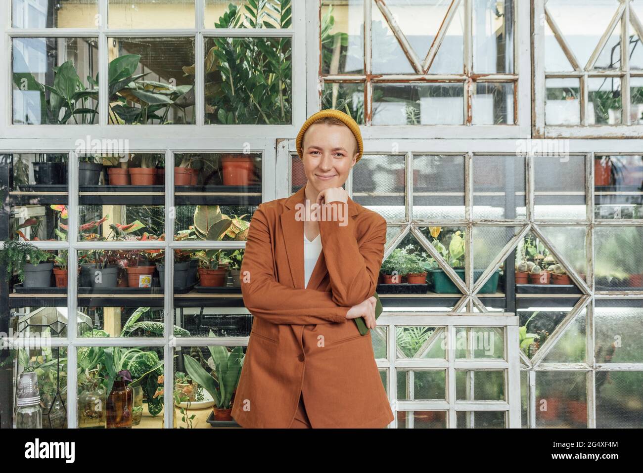 Geschäftsfrau mit der Hand auf dem Kinn, die im grünen Büro steht Stockfoto