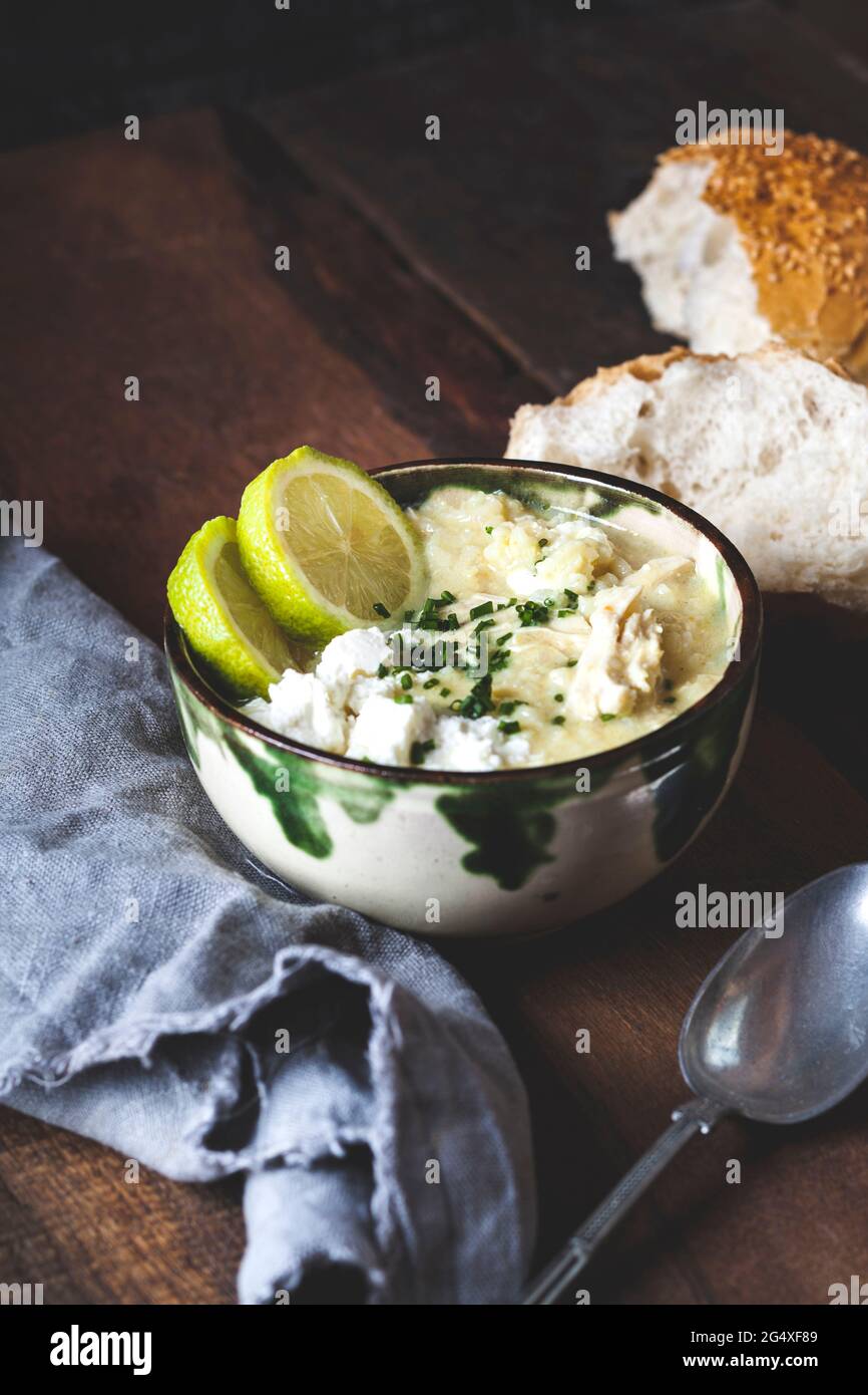 Schüssel mit griechischer Avgolemono-Suppe mit Reis, Zitronenscheiben und Brot Stockfoto