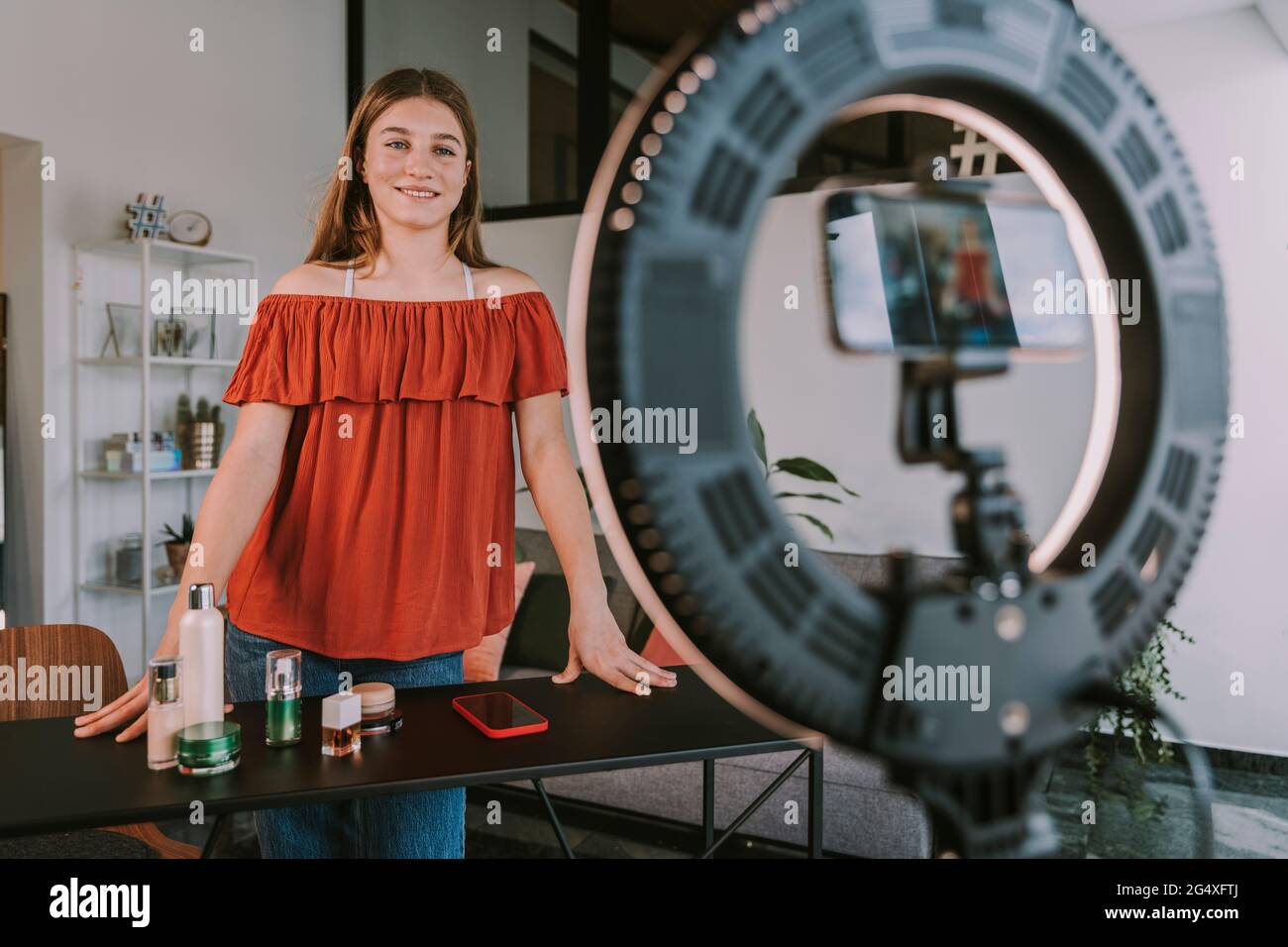 Lächelnde weibliche Influencerin mit Beauty-Produkten vlogging zu Hause Workshop Stockfoto