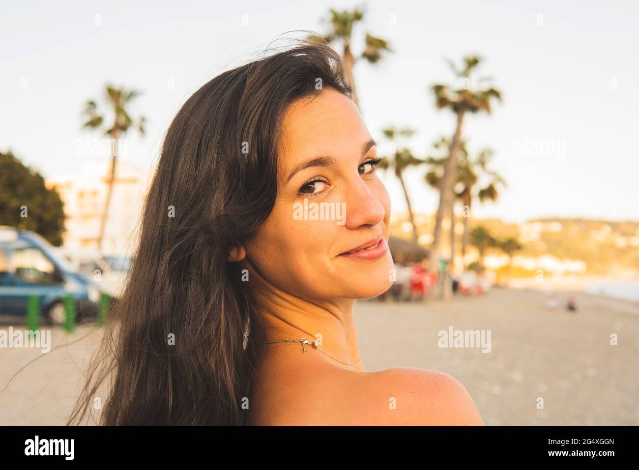 Schöne Frau, die über die Schulter auf den Strand blickt Stockfoto