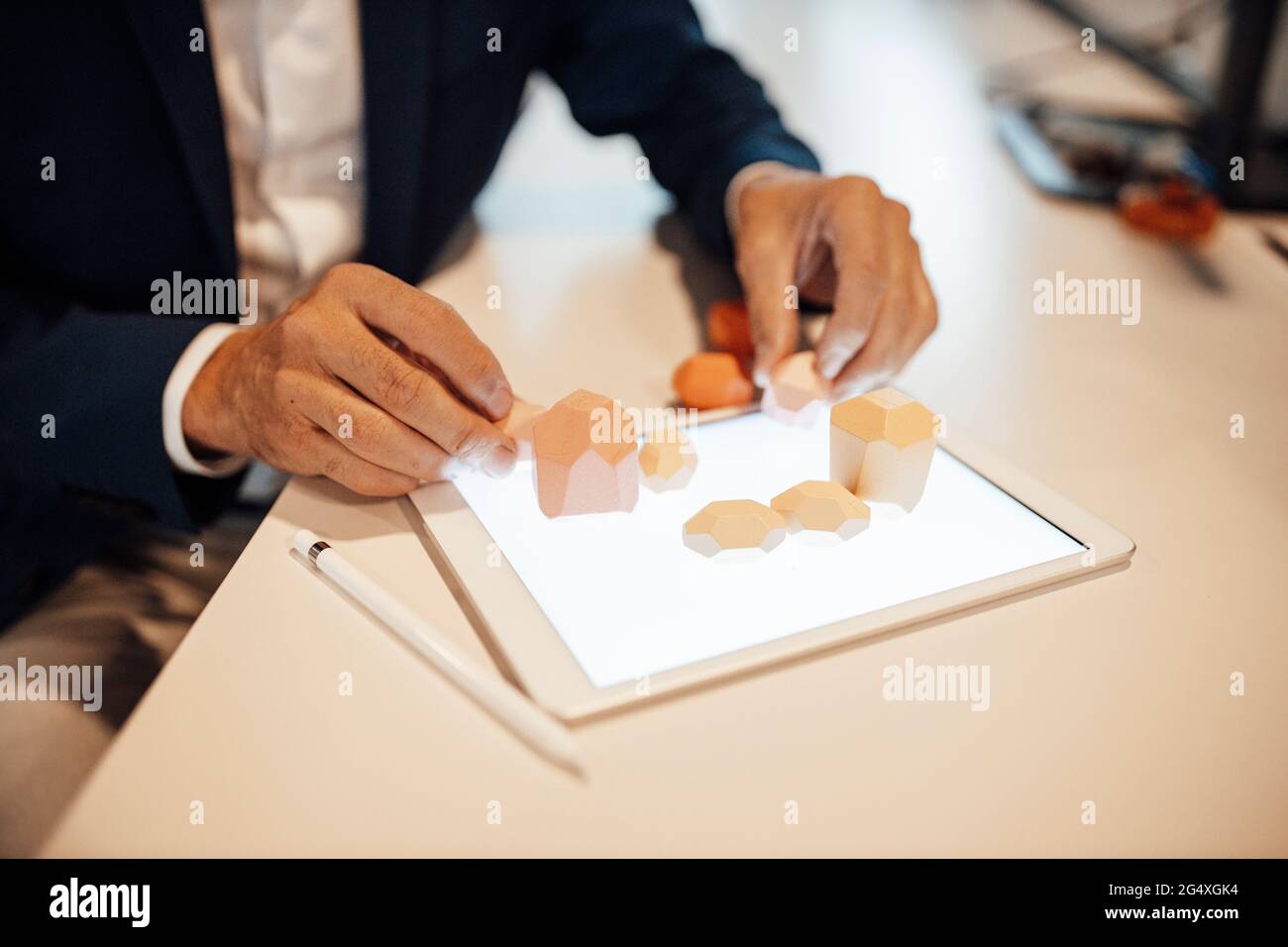 Leitender männlicher Unternehmer, der im Büro Holzfelsen auf einem digitalen Tablet sammelt Stockfoto