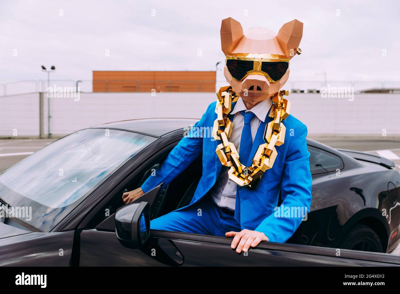 Lustige Figur trägt Tiermaske und blauen Business-Anzug im Auto Stockfoto