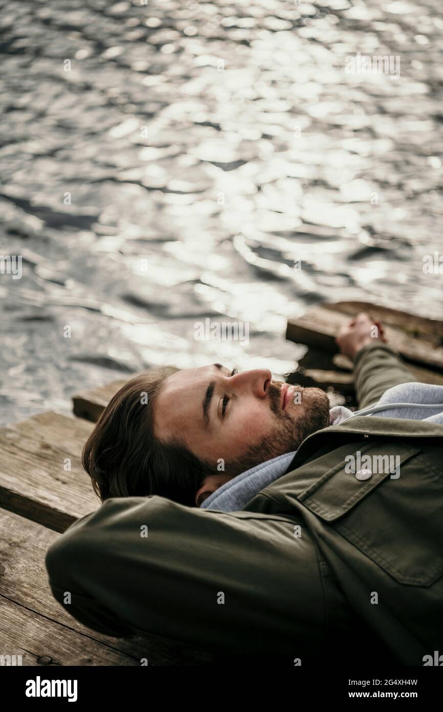 Lächelnder Mann, der am Pier über Seddinsee lag und träumte Stockfoto