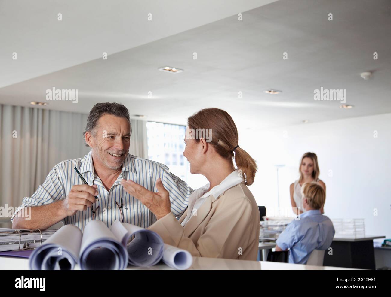 Männliche und weibliche Berufstätige diskutieren im Büro Stockfoto