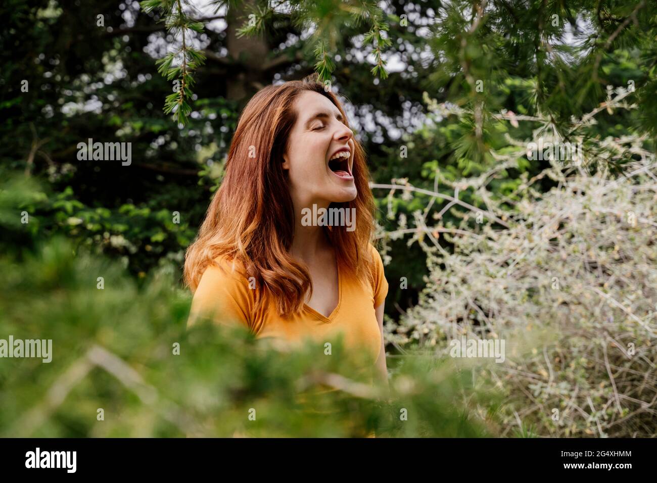 Rothaarige Frau, die im Garten mit offenem Mund schreit Stockfoto
