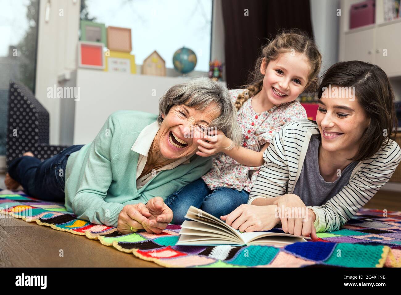 Familie mit mehreren Generationen lächelt, während sie zu Hause liegt Stockfoto