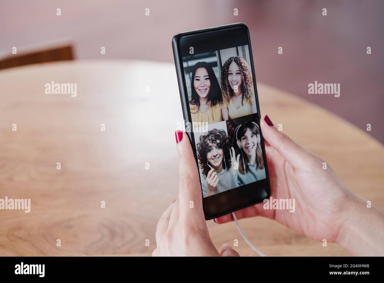 Junge Frau, die während eines Videoanrufs über ein Smartphone im Café mit weiblichen Freunden spricht Stockfoto