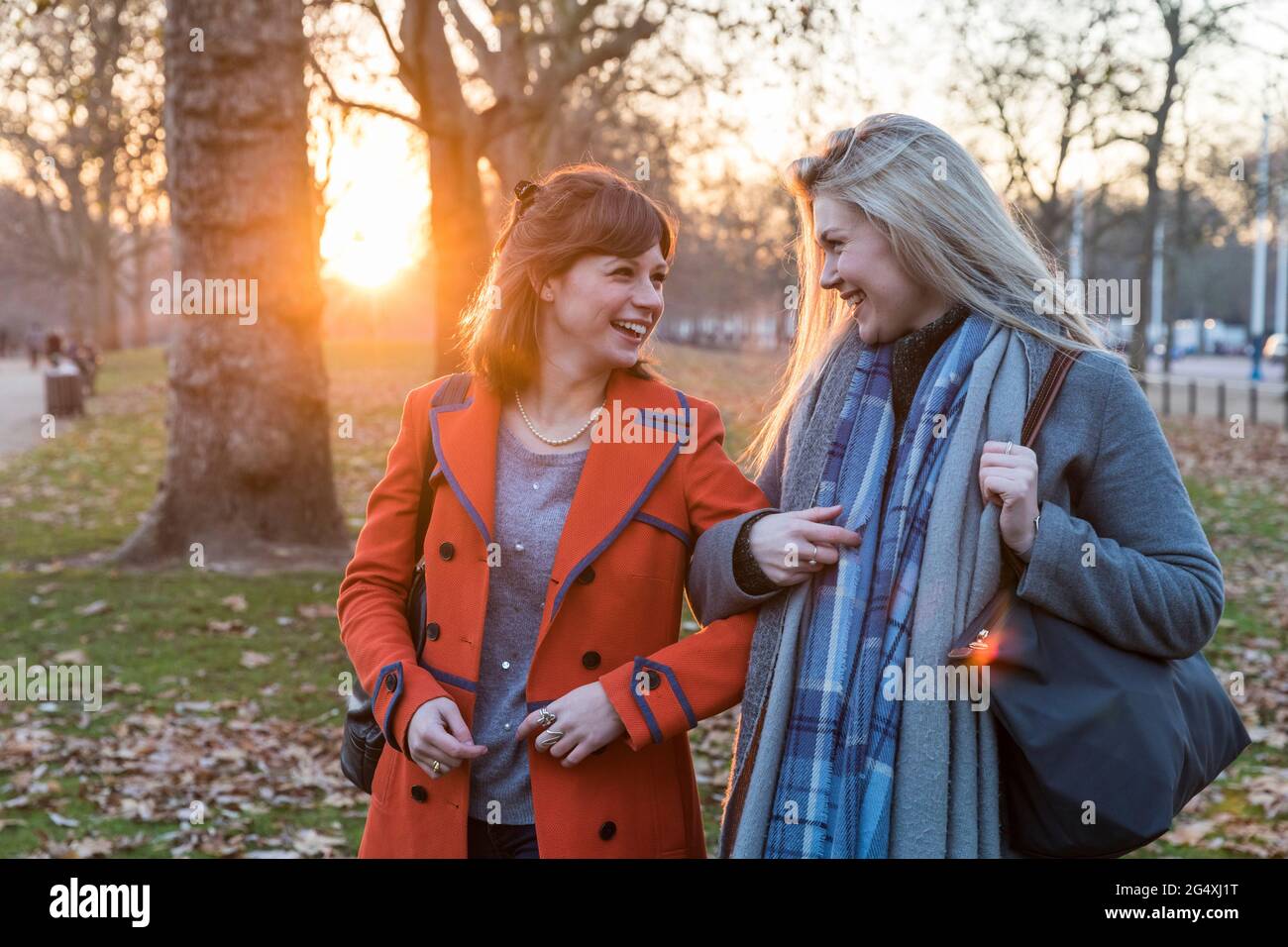 Fröhliche Freundinnen, die sich gegenseitig angusten, während sie im Park stehen Stockfoto