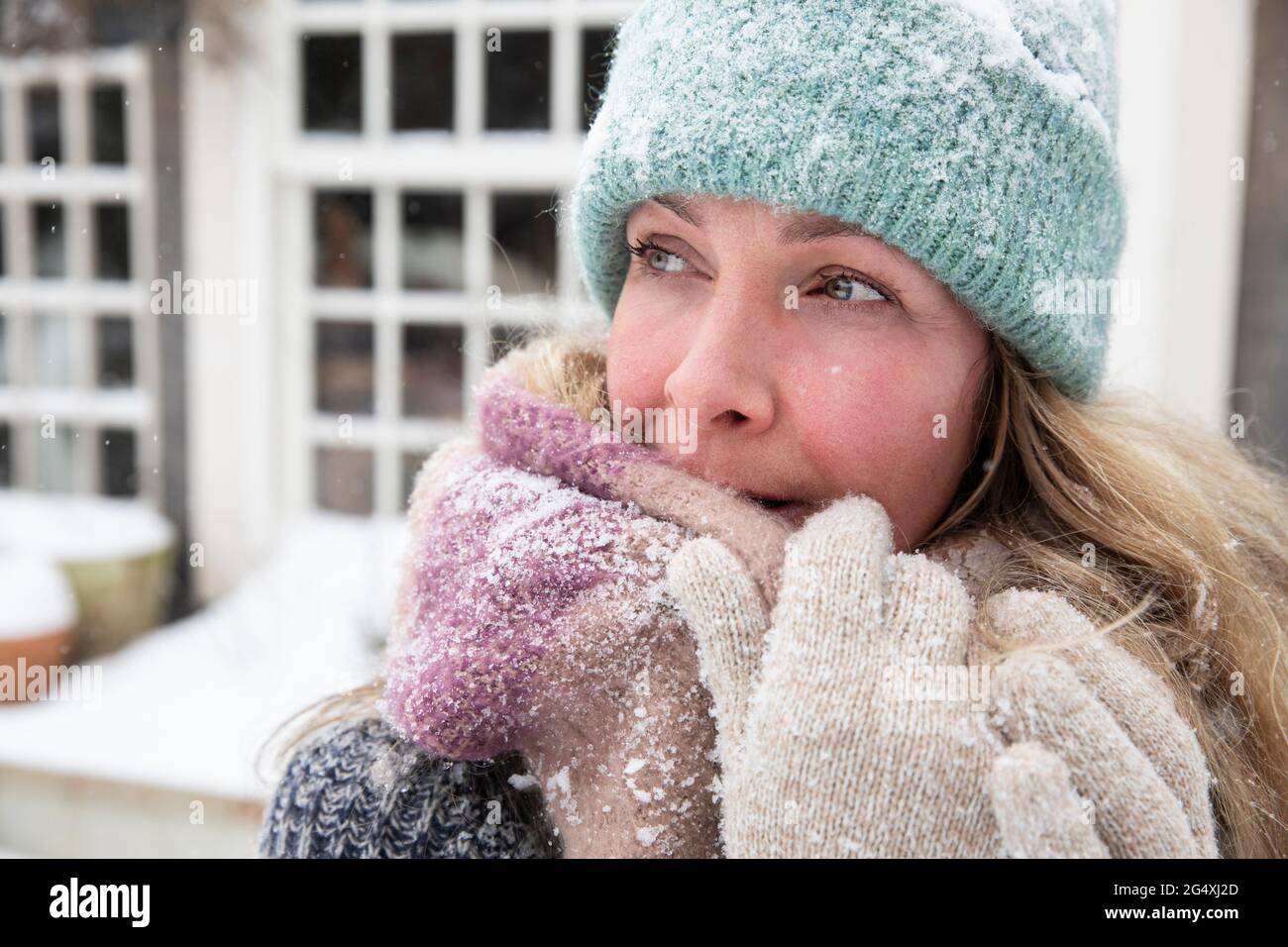 Blonde Frau bedeckt den Mund mit Schal, während sie wegschaut Stockfoto