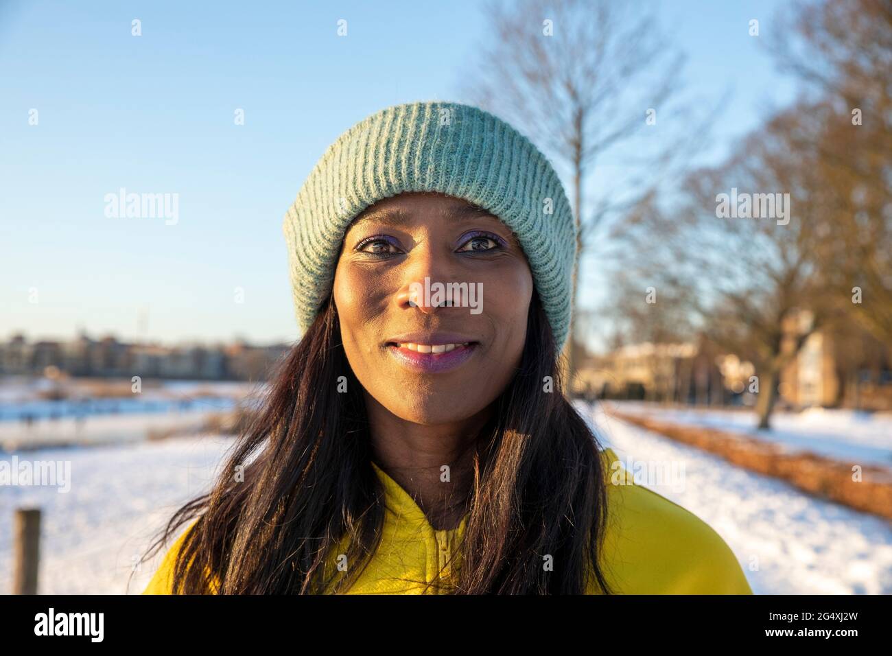 Schöne lächelnde Frau trägt blauen Strickhut im Winter Stockfoto