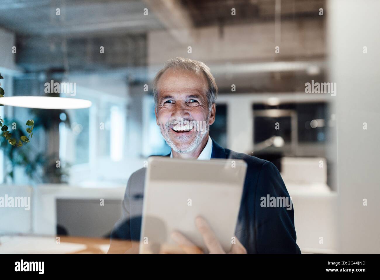 Fröhlicher Geschäftsmann mit digitalem Tablet im Büro Stockfoto