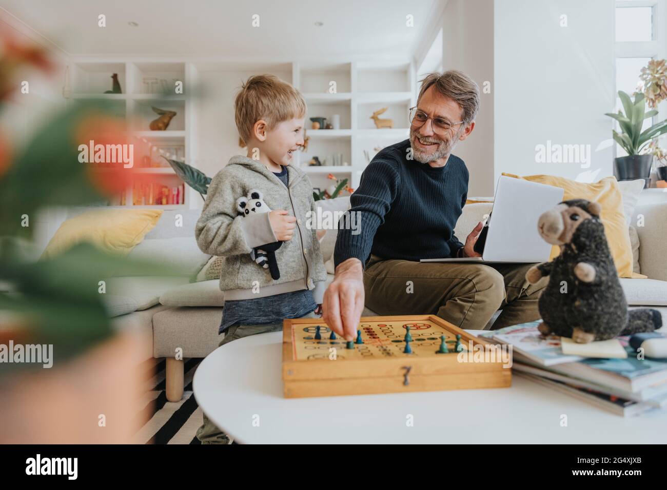 Glücklicher Vater spielt Ludo-Spiel mit Sohn zu Hause Stockfoto