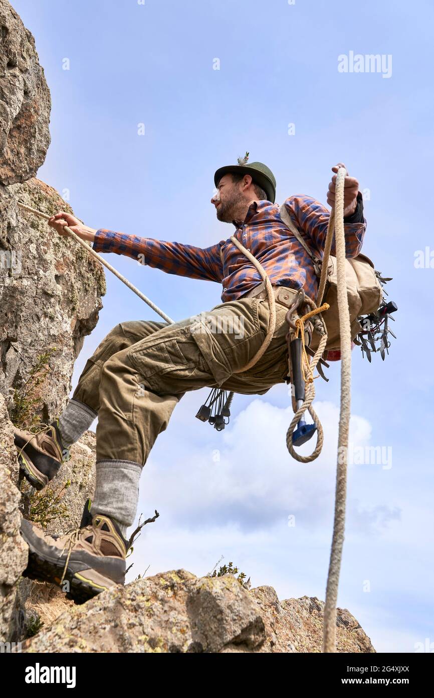 Bergsteiger mit Sicherheitsgurt am sonnigen Tag auf den Berg klettern Stockfoto