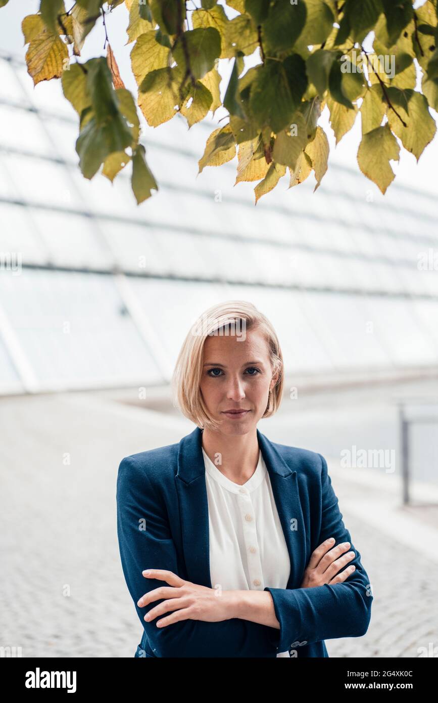 Unternehmerin mit gekreuzten Armen, die im Büropark steht Stockfoto