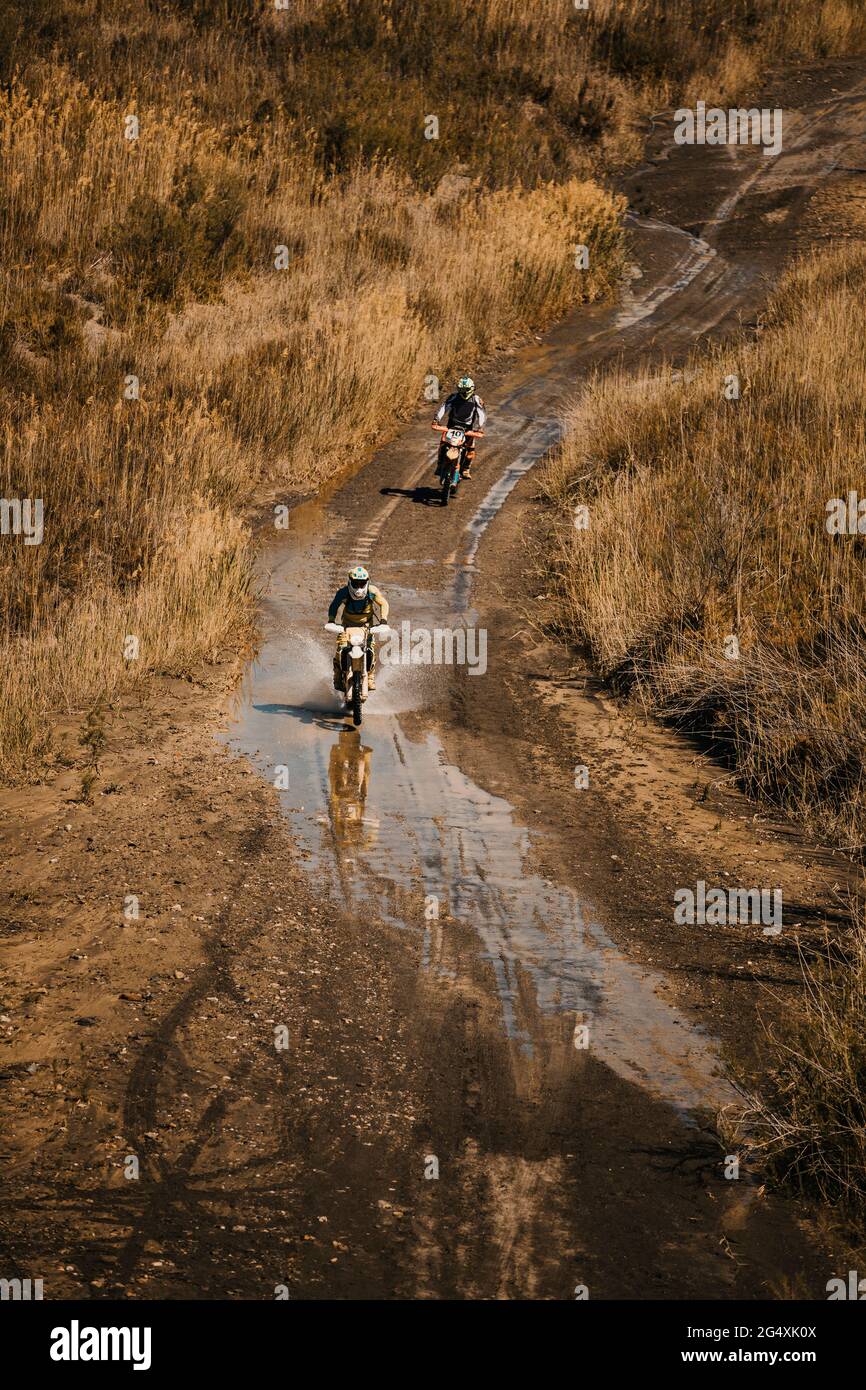 Männliche Biker mit auf nasser Straße während Enduro-Motorrad-Rennen Stockfoto