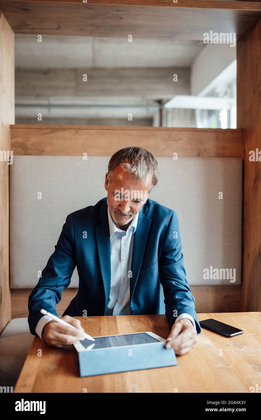 Leitender männlicher Unternehmer, der im Büro an digitalen Tablets arbeitet Stockfoto