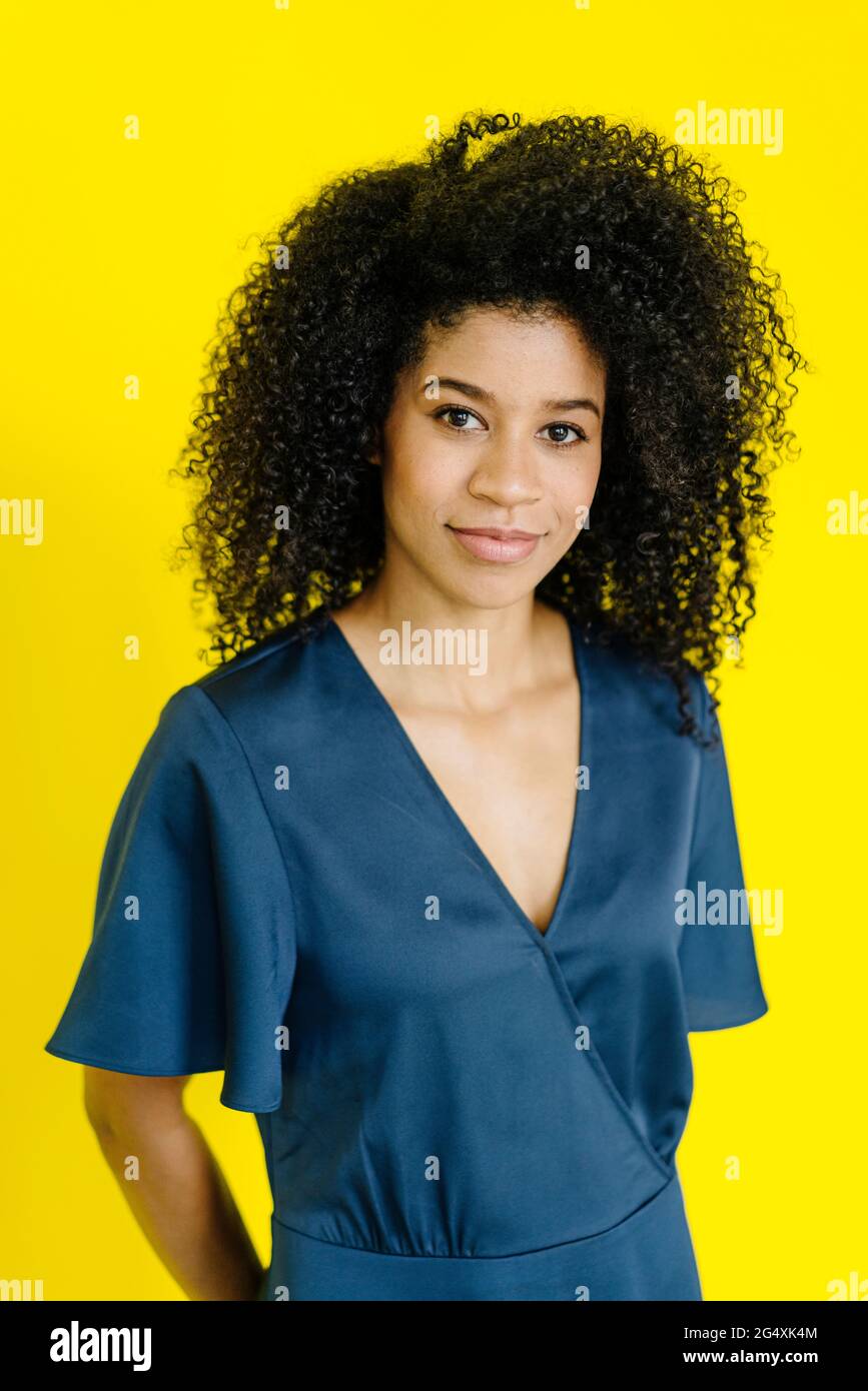 Geschäftsfrau mit krausem Haar, das auf gelbem Hintergrund steht Stockfoto