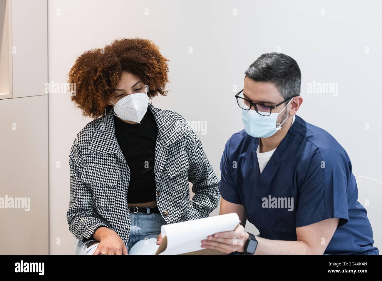 Männlicher Zahnarzt, der weiblichen Patienten in der Klinik medizinische Berichte erklärt Stockfoto
