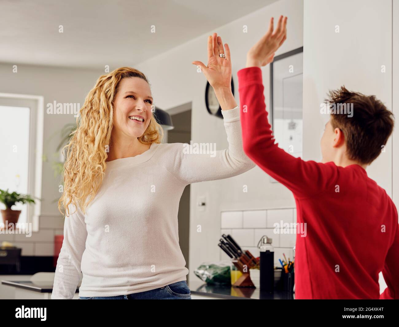 Fröhliche Mutter ermutigend Sohn mit hohen fünf in der Küche Stockfoto