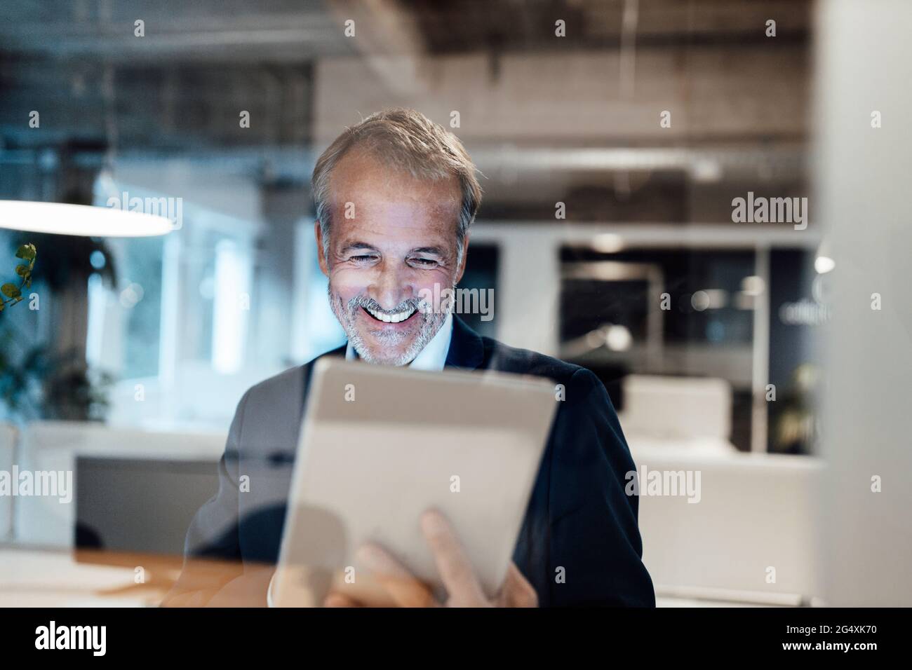 Leitender männlicher Unternehmer, der im Büro ein digitales Tablet verwendet Stockfoto