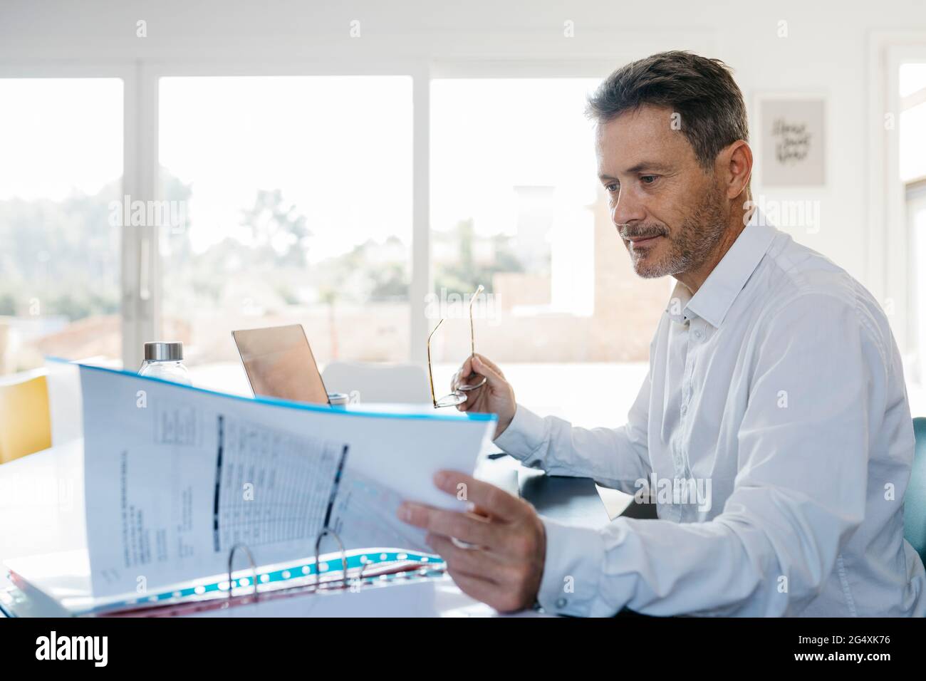 Geschäftsmann mit Brille, der im Home Office in einer Box-Datei sucht Stockfoto