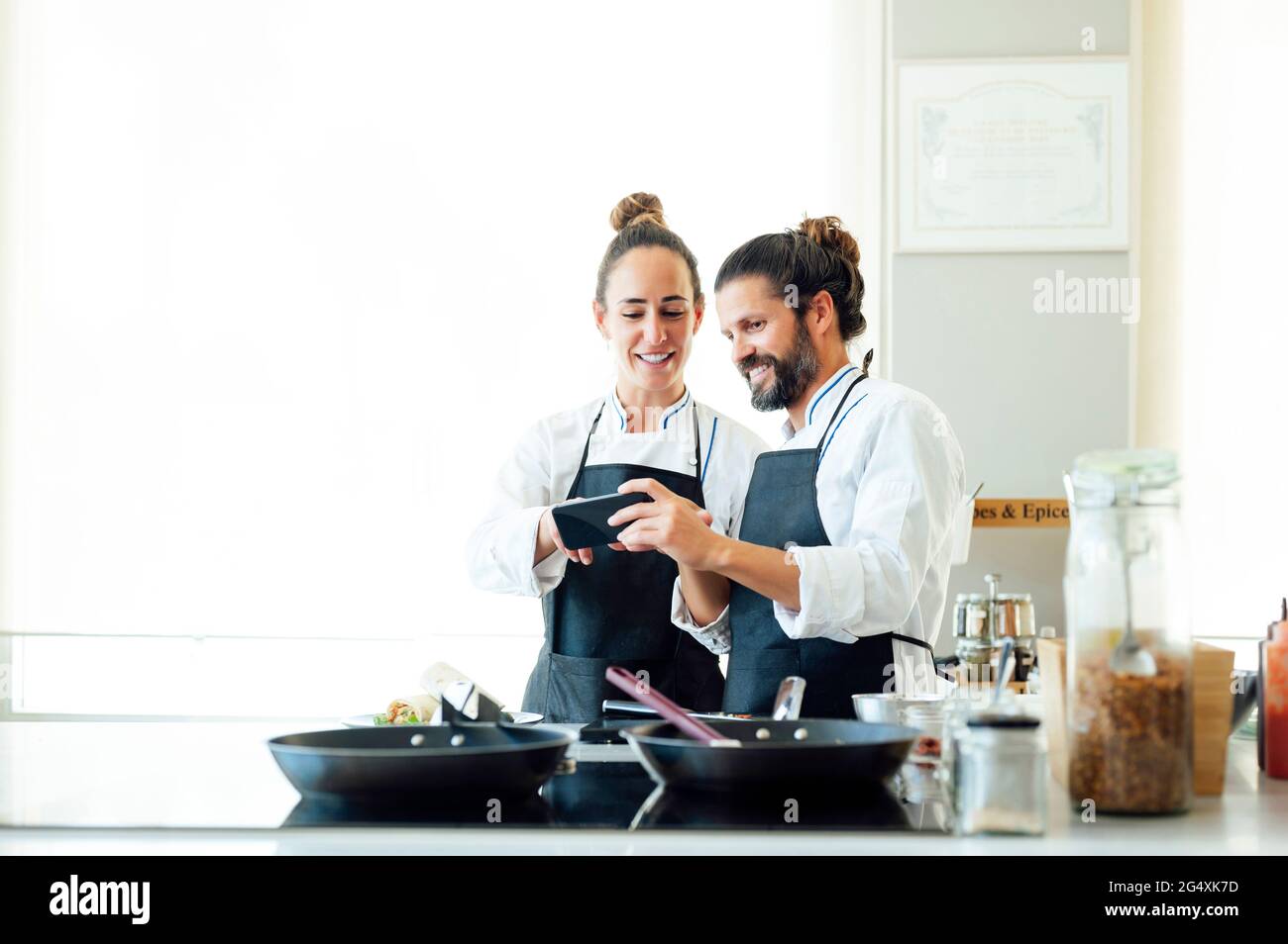 Professionelle Köche, die im Restaurant ein Mobiltelefon benutzen Stockfoto