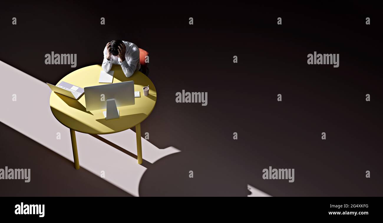 Geschäftsmann, der allein am Tisch in einem abgedunkelten Raum mit dem Kopf in den Händen sitzt Stockfoto