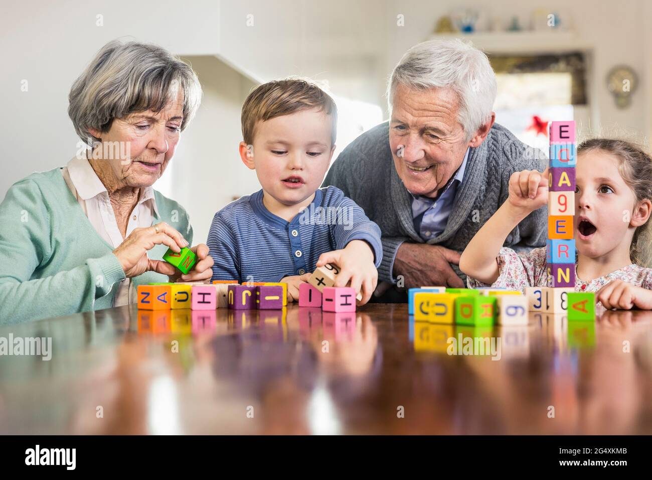 Kinder, die von Großeltern zu Hause mit Spielzeugblöcken spielen Stockfoto