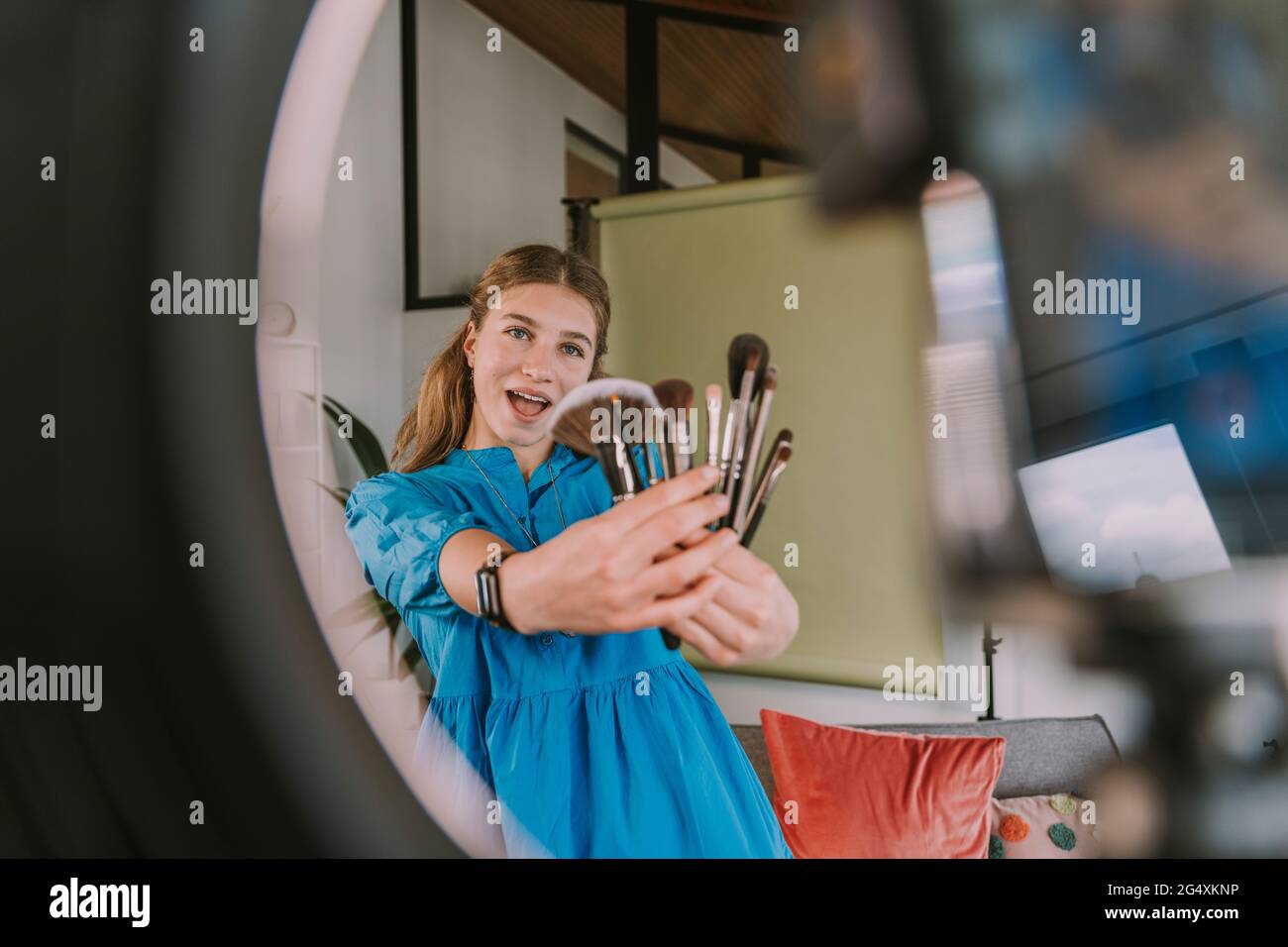 Teenager-Mädchen zeigt verschiedene Make-up-Pinsel, während Vlogging zu Hause Stockfoto