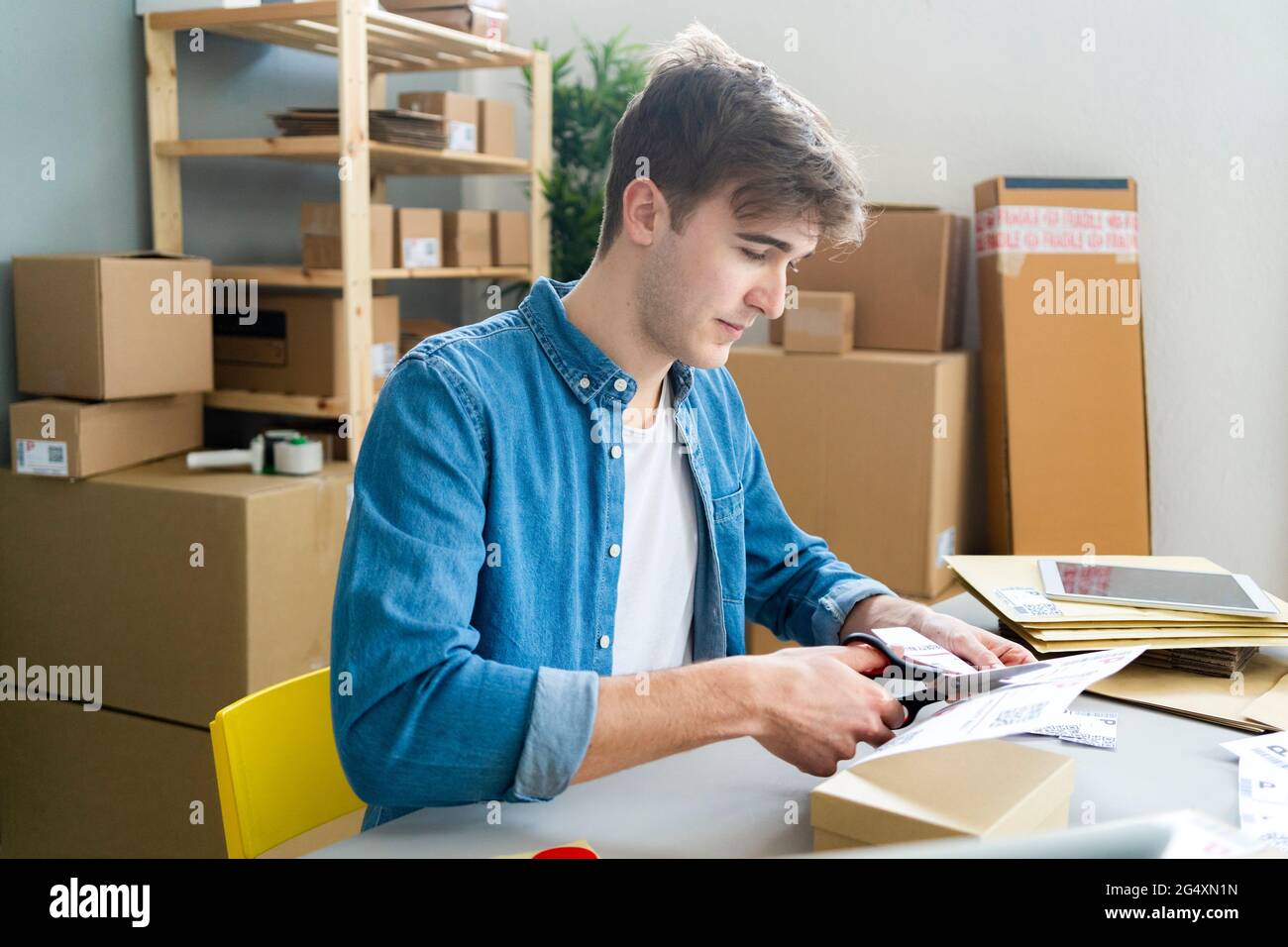 Ein Geschäftsmann schneidet am Schreibtisch ein Strichcode-Etikett ab Stockfoto