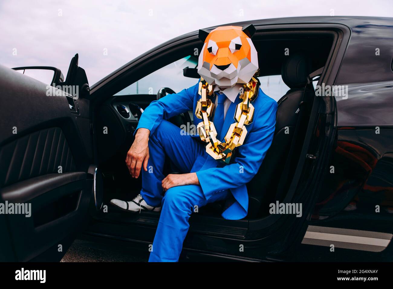Lustiger Charakter in Tiermaske und blauer Business-Anzug im Auto sitzen Stockfoto