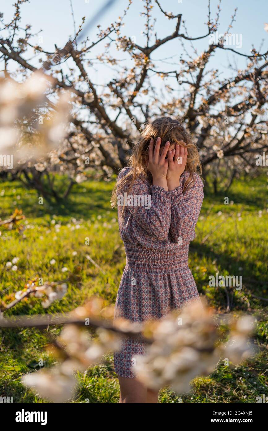 Frau mit Kopf in den Händen im Kirschgarten im Frühling Stockfoto