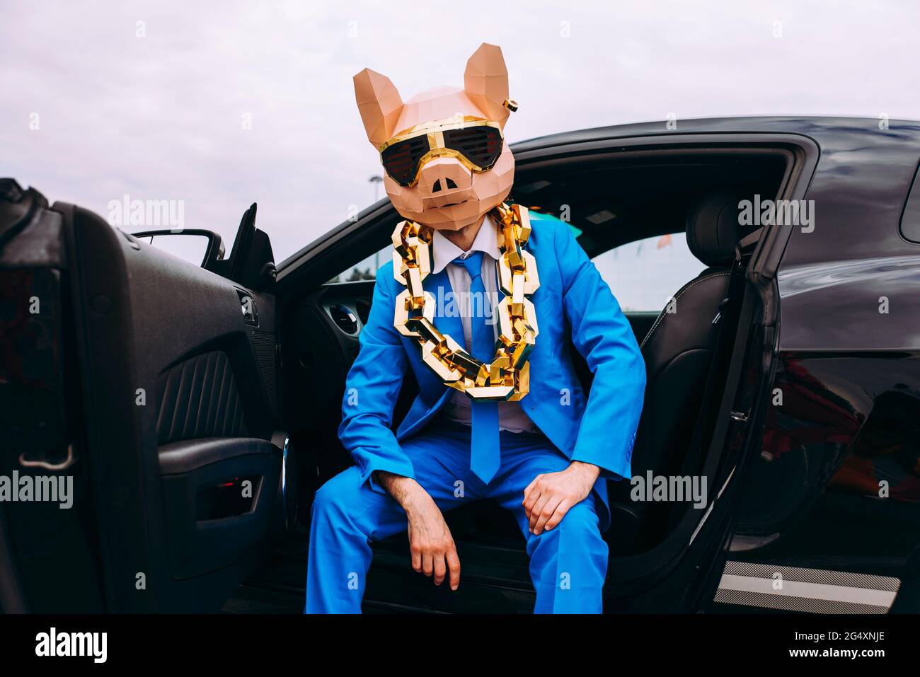 Lustiger Charakter in Tiermaske und blauer Business-Anzug im Auto sitzen Stockfoto