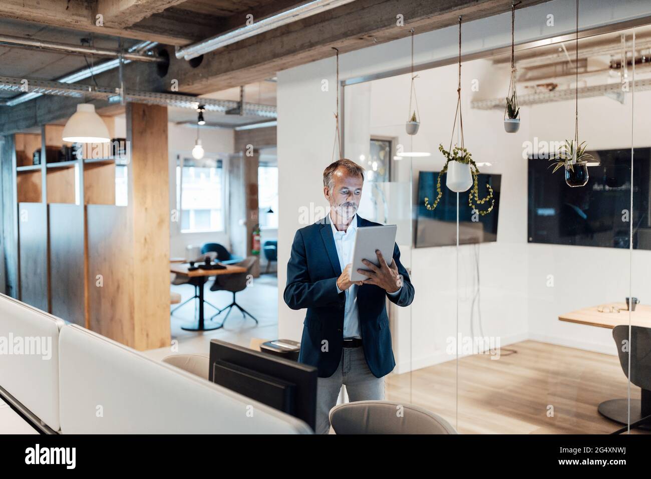 Leitender männlicher Unternehmer, der im Büro ein digitales Tablet verwendet Stockfoto