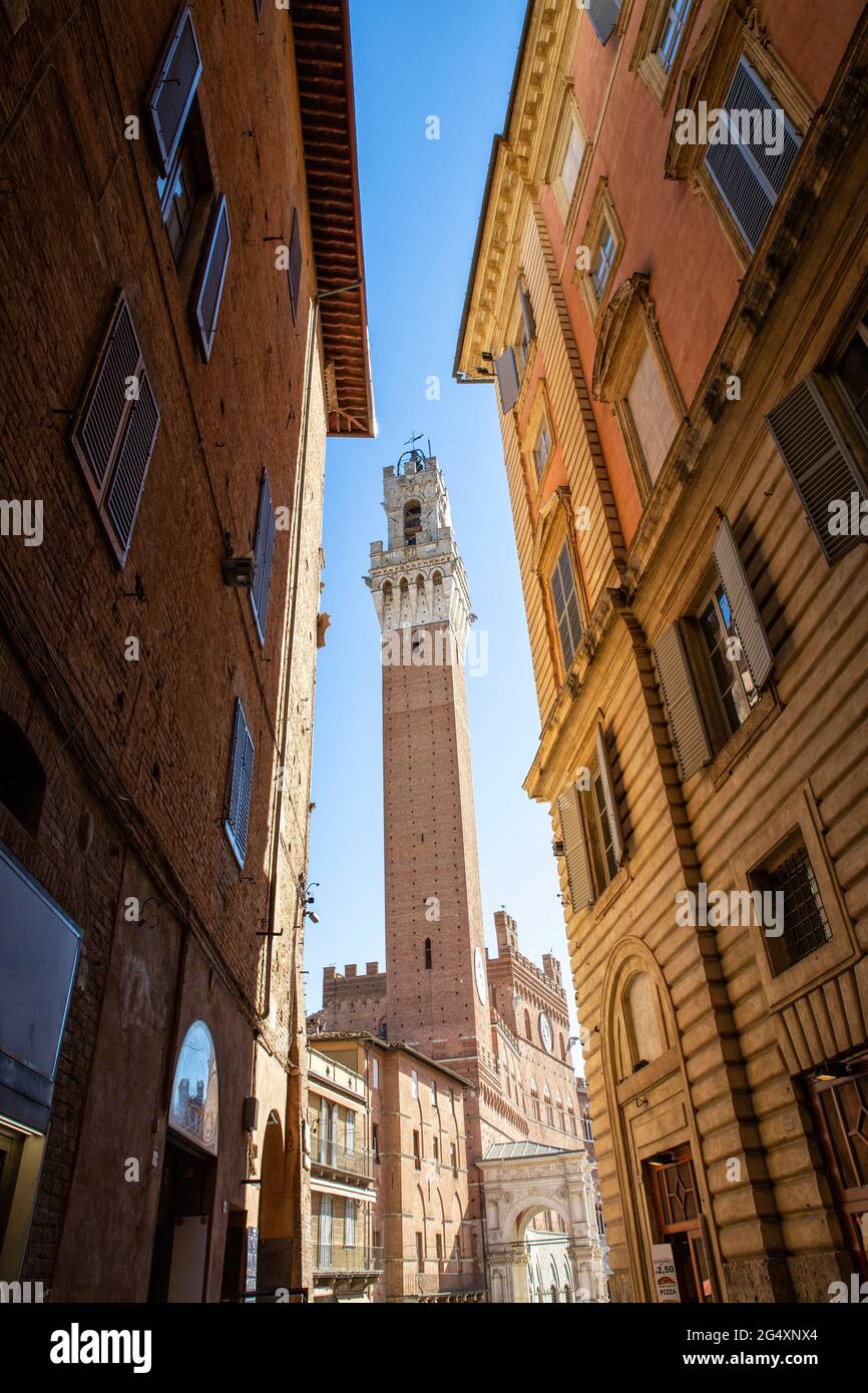 Italien, Toskana, Siena, Blick auf Torre del Mangia zwischen zwei Stadthäusern Stockfoto