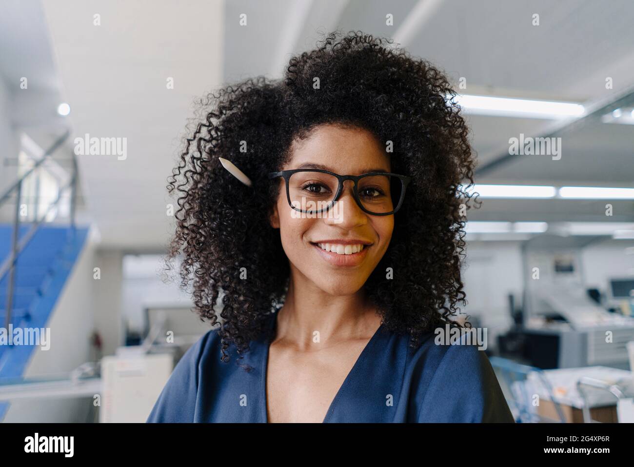 Lächelnde Geschäftsfrau mit krausem Haar in der Industrie Stockfoto