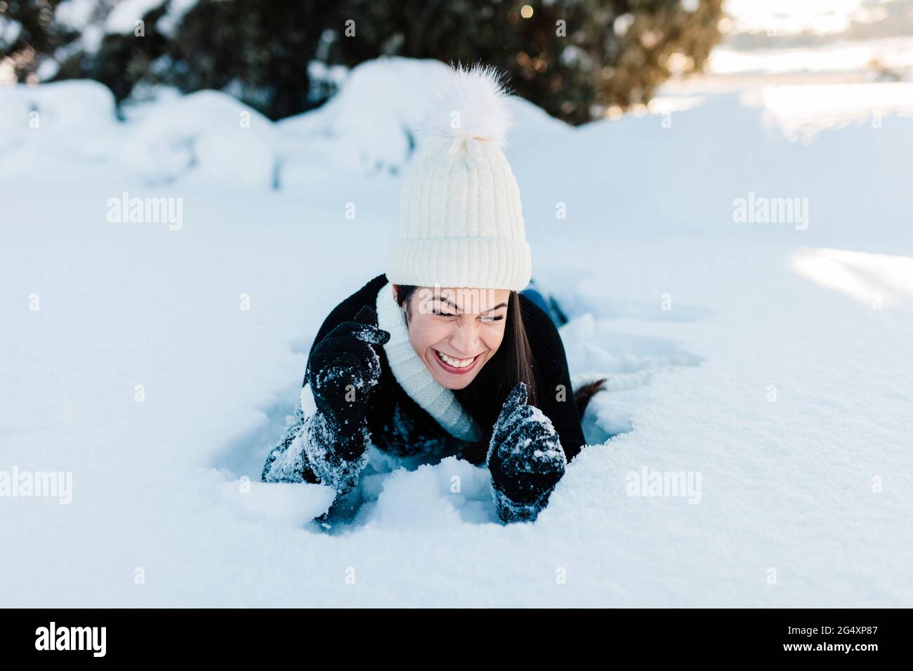 Fröhliche Frau, die auf tiefem Schnee liegt Stockfoto