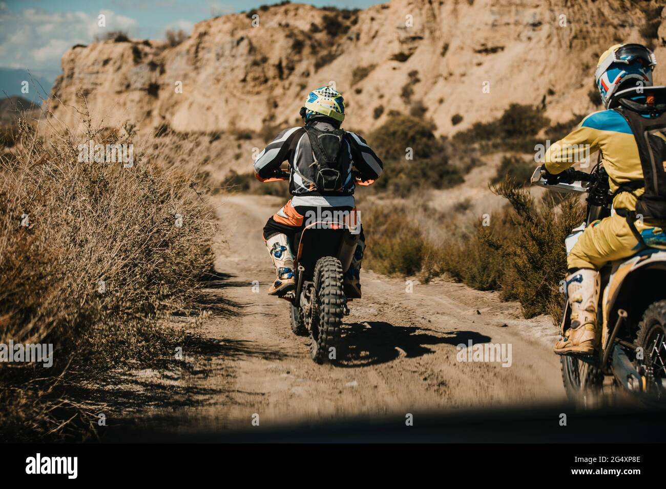Männlicher Biker mit schützender Sportbekleidung fährt Motorräder auf Wüstenstraße Stockfoto
