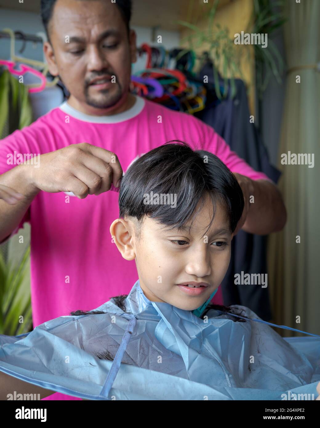 Asiatisches Kind bekommt Haarschnitt zu Hause vom Vater. Stockfoto