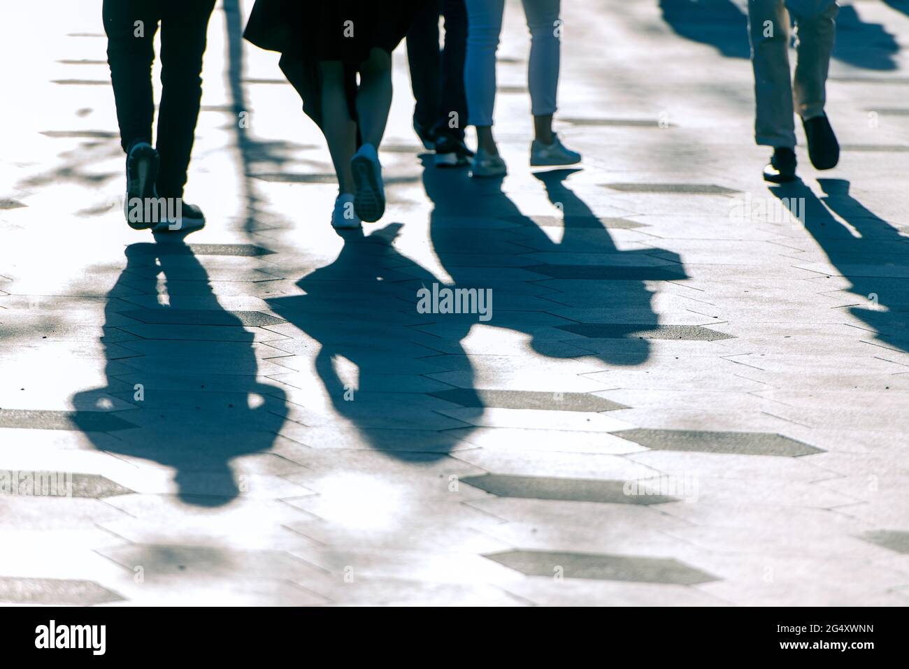 Schatten und Silhouetten von Menschen auf einer Straße während des sonnigen Abends. Stockfoto