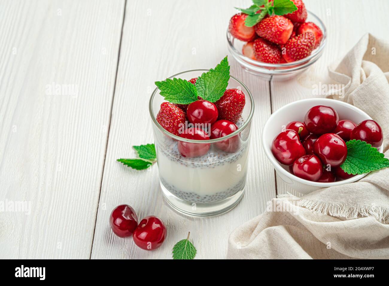 Milchdessert mit Chiasamen und frischen Kirschen und Erdbeeren. Cremiger Pudding auf weißem Hintergrund. Stockfoto