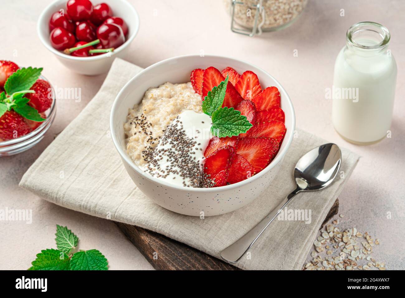 Haferbrei mit frischen Erdbeeren auf hellrosa Hintergrund. Stockfoto