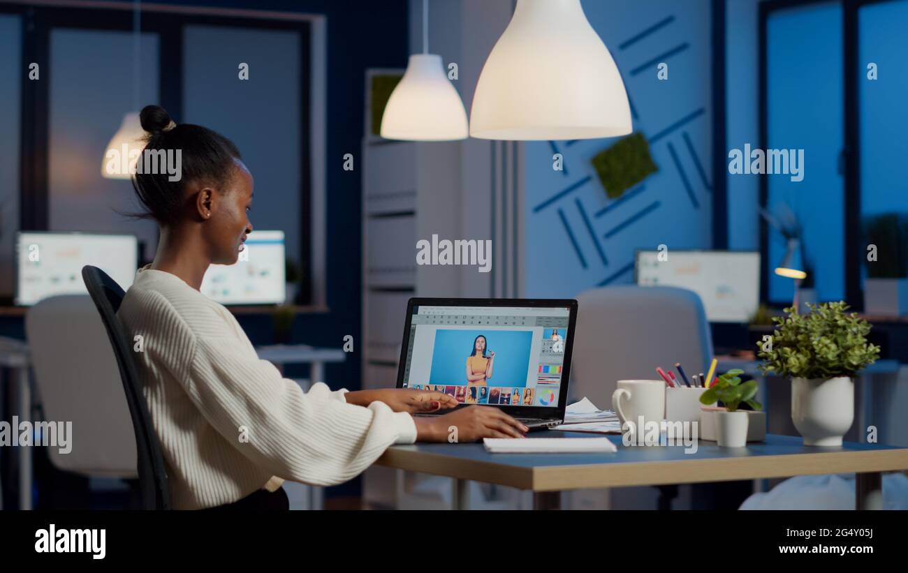 Dunkelhäutiger Freiberufler Retuscherin Frau, die Überstunden am Laptop mit Fotobearbeitungssoftware arbeitet. Professioneller Grafikeditor Retusche Foto eines Kunden in der Nacht im Home Office auf Performance-pc Stockfoto