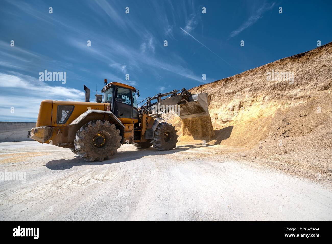 Ein Radlader trägt einen vollen Eimer mit Tierfutter. Stockfoto