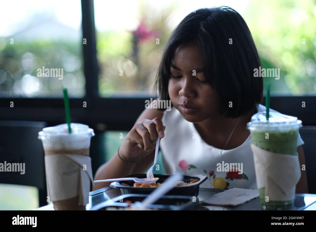 Ein thailändisches Mädchen im Teenageralter frühstückt, was offensichtlich sehr angenehm ist Stockfoto