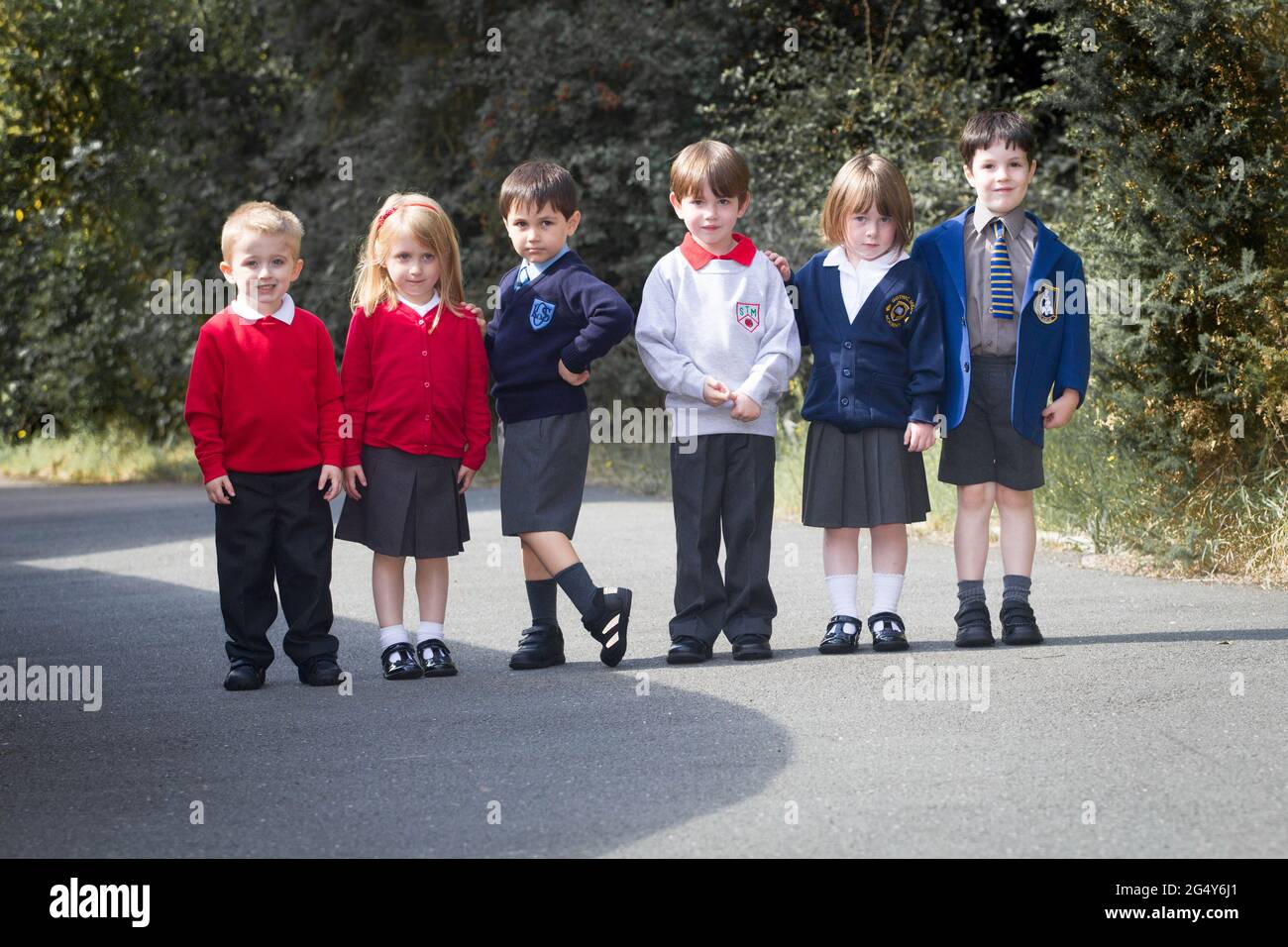 Kleine Kinder tragen verschiedene Schuluniformen Stockfoto