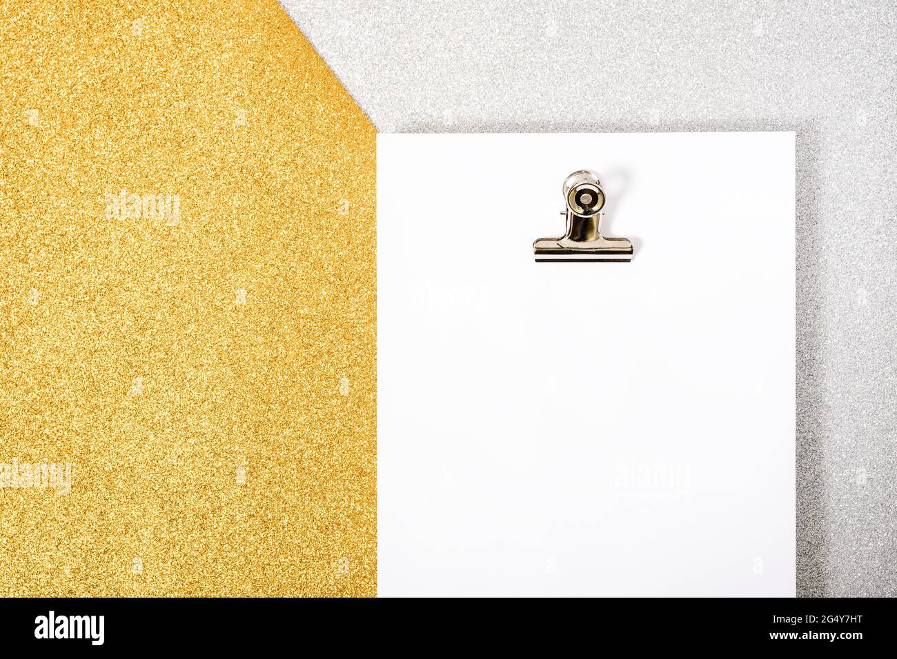 Foto eines White Foil Packs und einer Büroklammer auf einem texturierten Silber- und Goldhintergrund. Das Foto hat einen Kopierraum, es wird von einem Überkopfpo aufgenommen Stockfoto