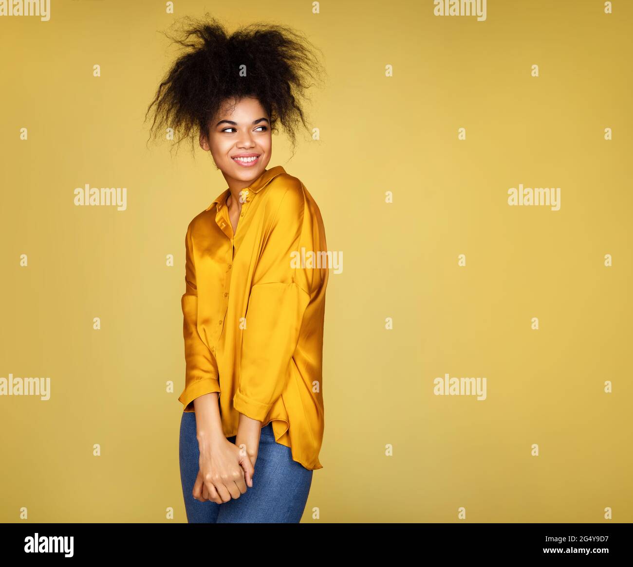 Attraktive schüchterne Mädchen, Blick beiseite. Foto von afroamerikanischen Mädchen auf gelbem Hintergrund Stockfoto