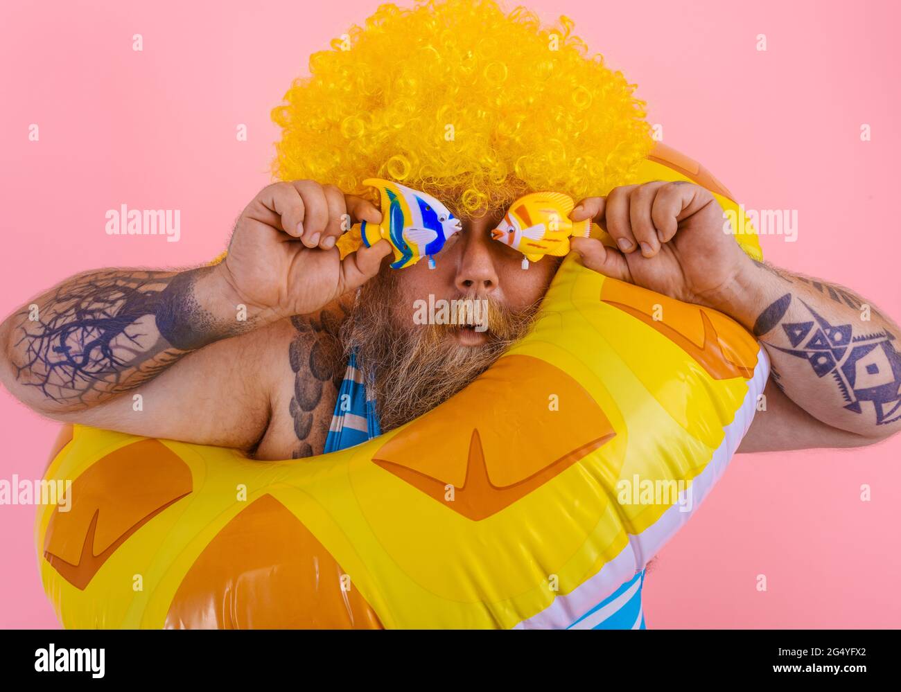 Ein fetter Mann mit Perücke im Kopf ist bereit, mit einem  Donut-Lebensretter zu schwimmen Stockfotografie - Alamy